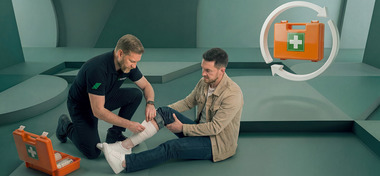 EHBO instructeur laat zien hoe je een wond aan het been van een cursist verbindt tijdens de EHBO cursus