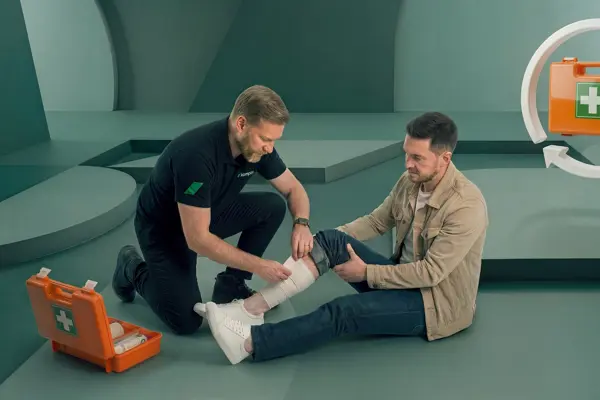 EHBO instructeur laat zien hoe je een wond aan het been van een cursist verbindt tijdens de EHBO cursus