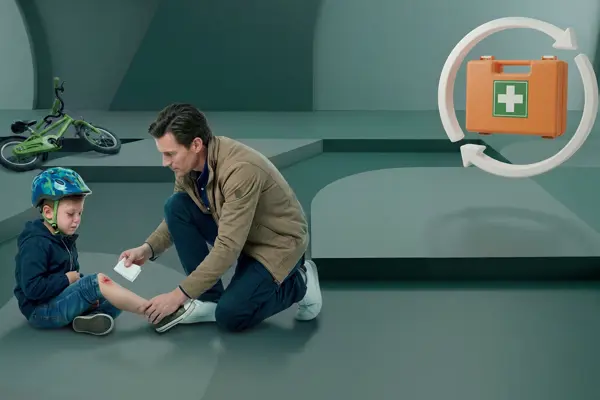 Vader dekt de wond af van zijn kind dat van de fiets is gevallen tijdens de cursus EHBO voor kinderen