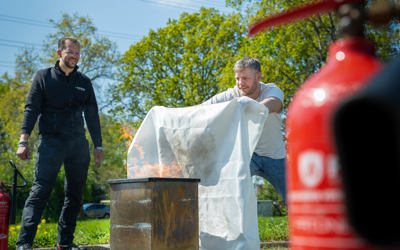 Cursisten oefenen buiten met een brandblusser onder begeleiding van een BHV instructeur